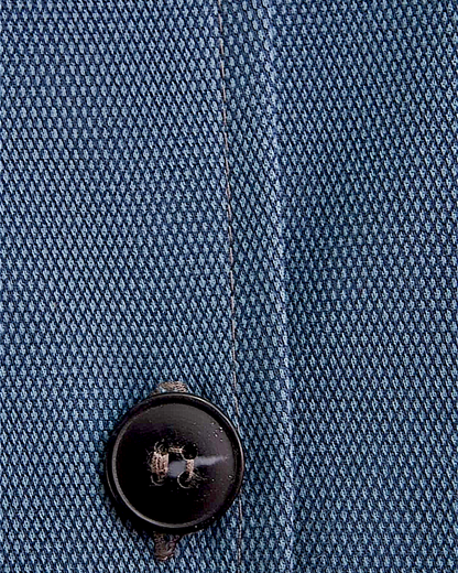 Close-up of Lefke Legacy steel blue cotton jubba fabric showing fine weave texture and a dark button detail.